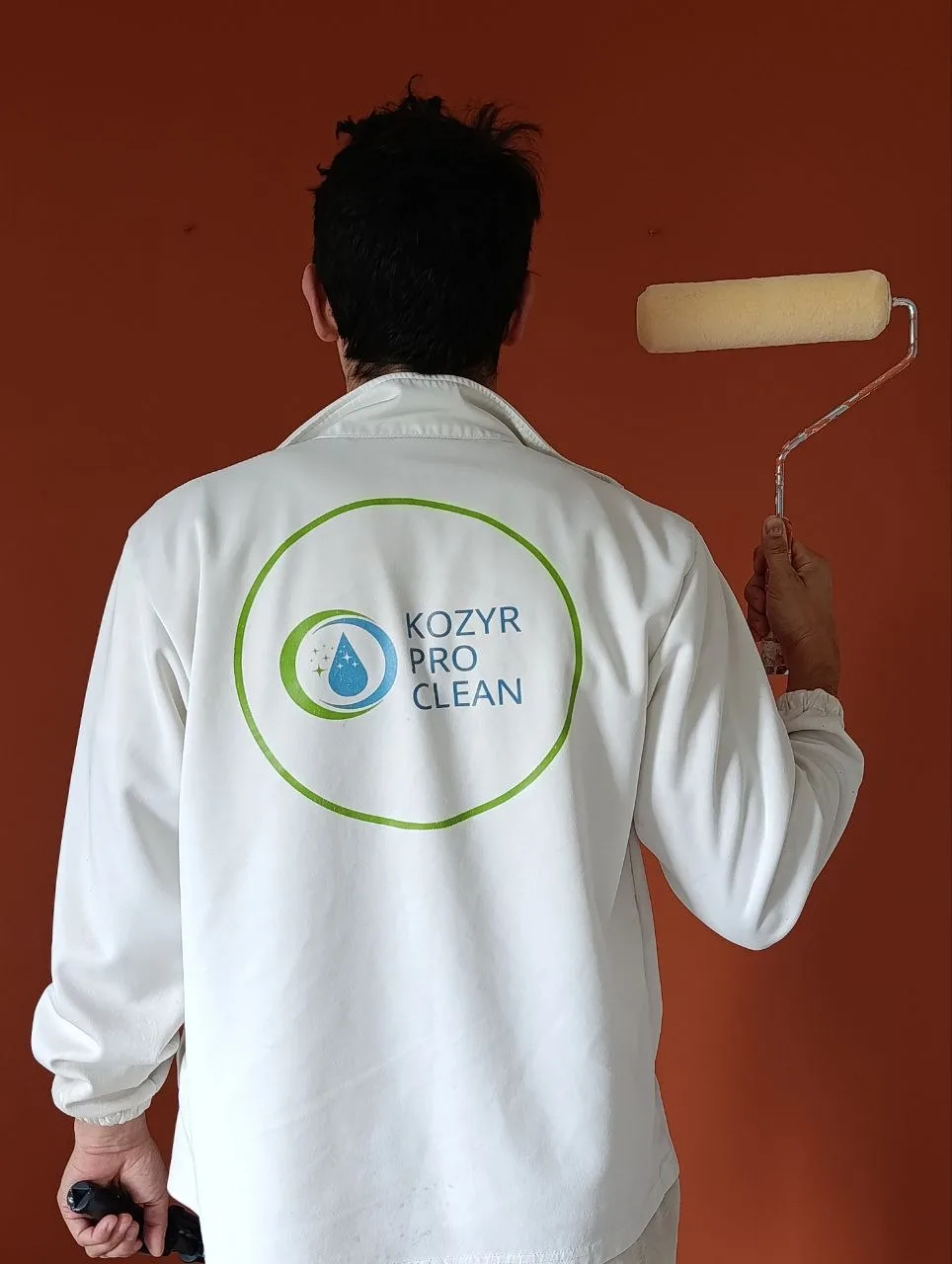 Kozyr Pro Paint: Yevhen with a paint roller in front of a freshly painted terracotta wall